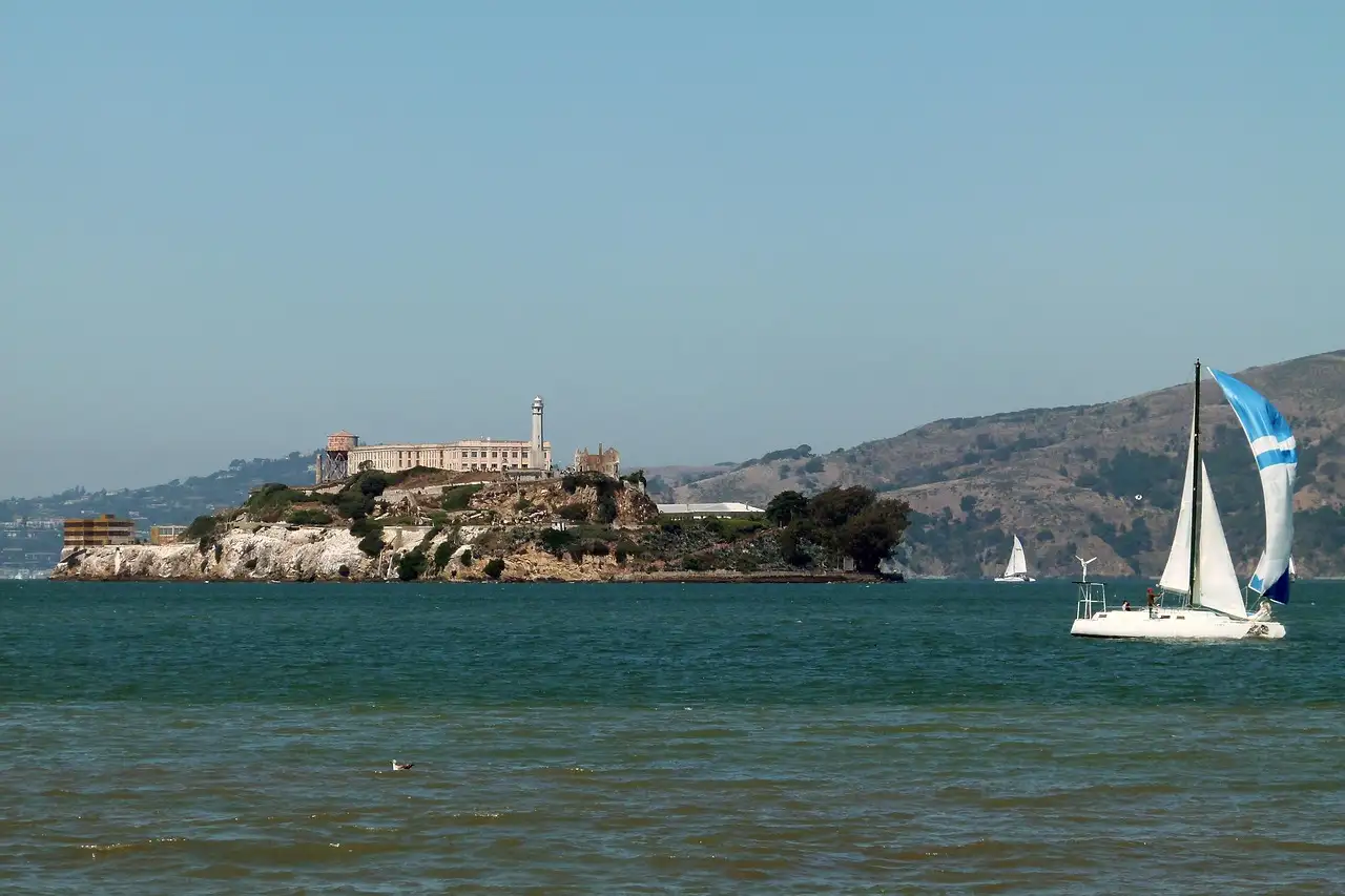 A sailboat passing Alcatraz Island on the bay
