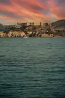 Alcatraz Island under a red sunset sky, seen across the bay