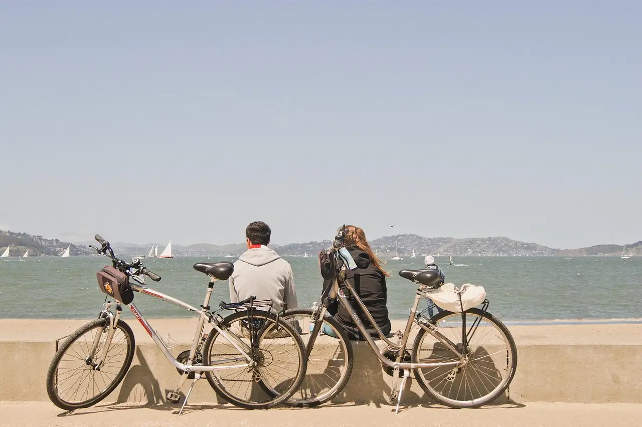 Two bicycles parked on the San Francisco waterfront, looking out over the bay