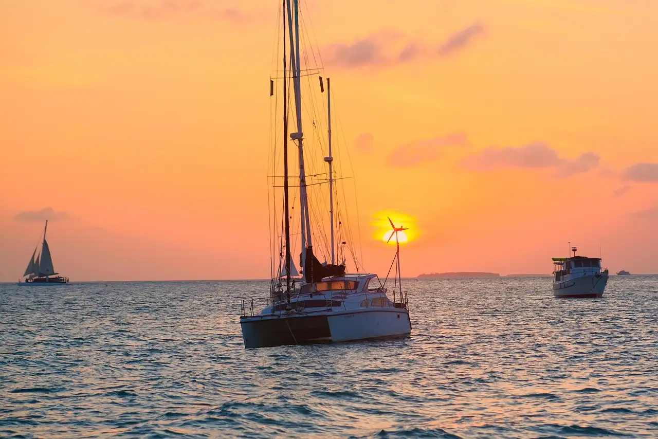 A catamaran on calm water at sunset, with other boats nearby