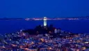 Coit Tower on Telegraph Hill at dusk, with the bay behind