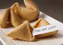 Fortune cookies on a plate, one with its paper slip showing