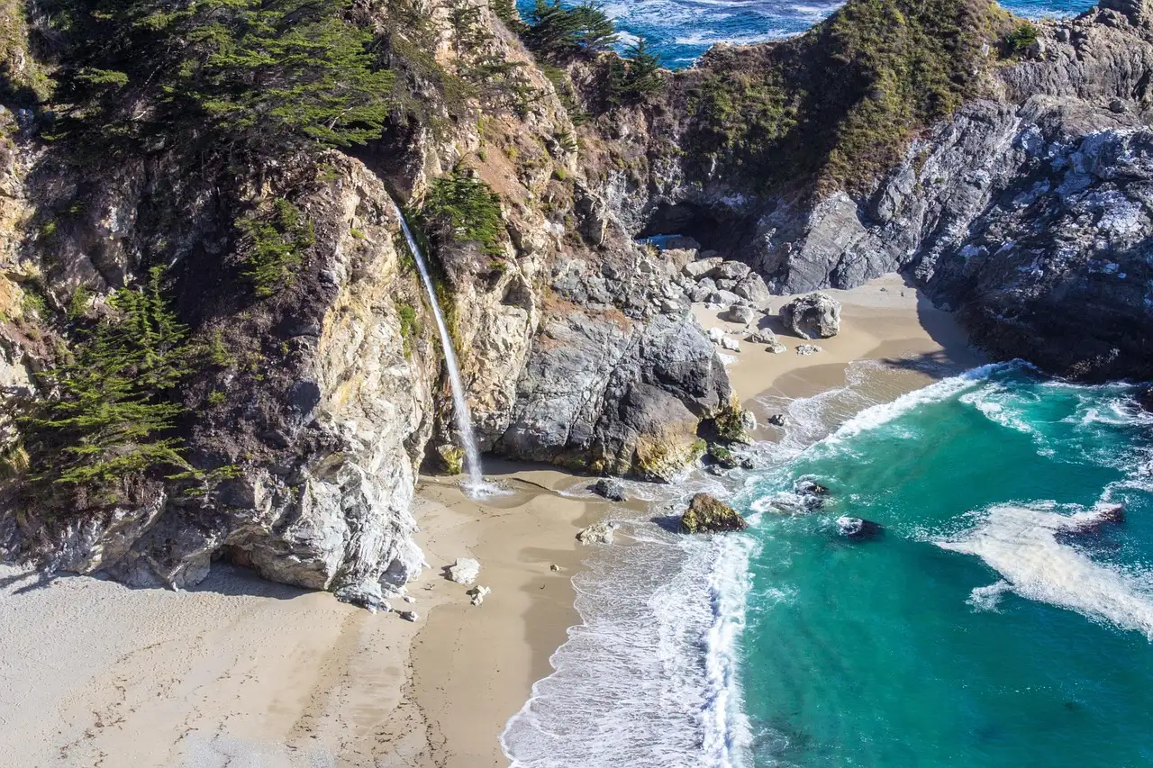 McWay Falls dropping onto the beach of a turquoise cove in Big Sur