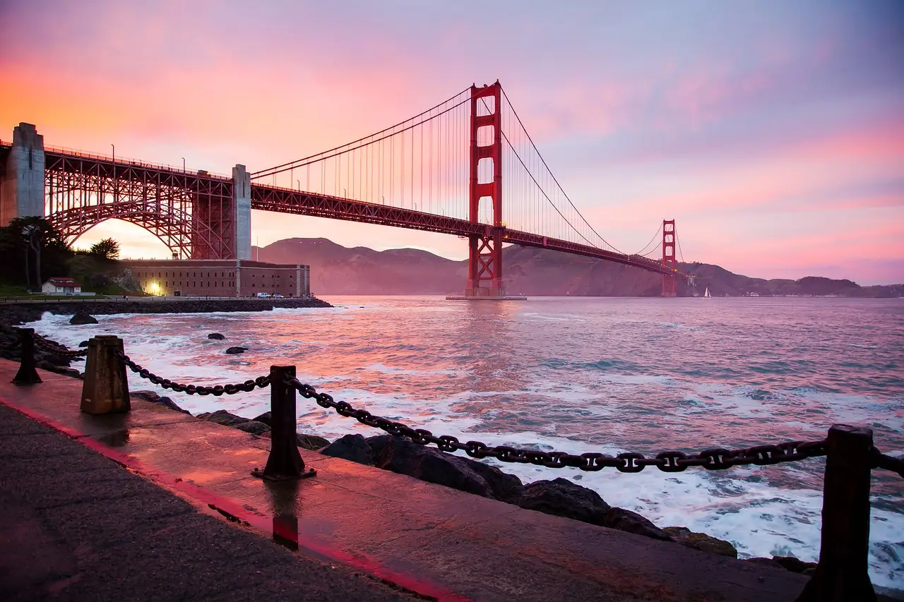 The Golden Gate Bridge at sunset with pink clouds seen from the waterfront near Fort Point