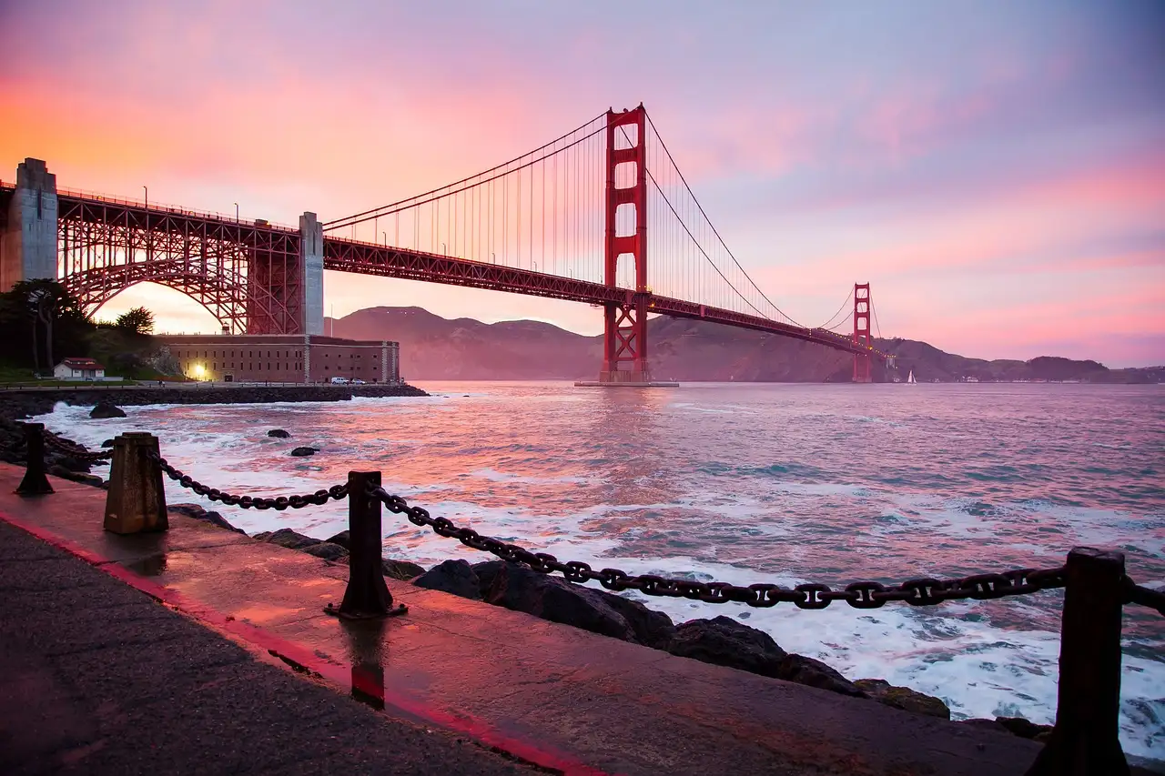 The Golden Gate Bridge at sunset with pink clouds seen from the waterfront near Fort Point