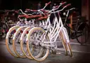 A row of white city bicycles parked together