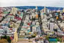 Colorful houses on San Francisco's hills seen from above, with a church spire in front