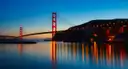 The Golden Gate Bridge and its lights reflected in the bay at dusk