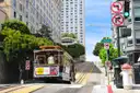A San Francisco cable car climbing a steep street past tall buildings