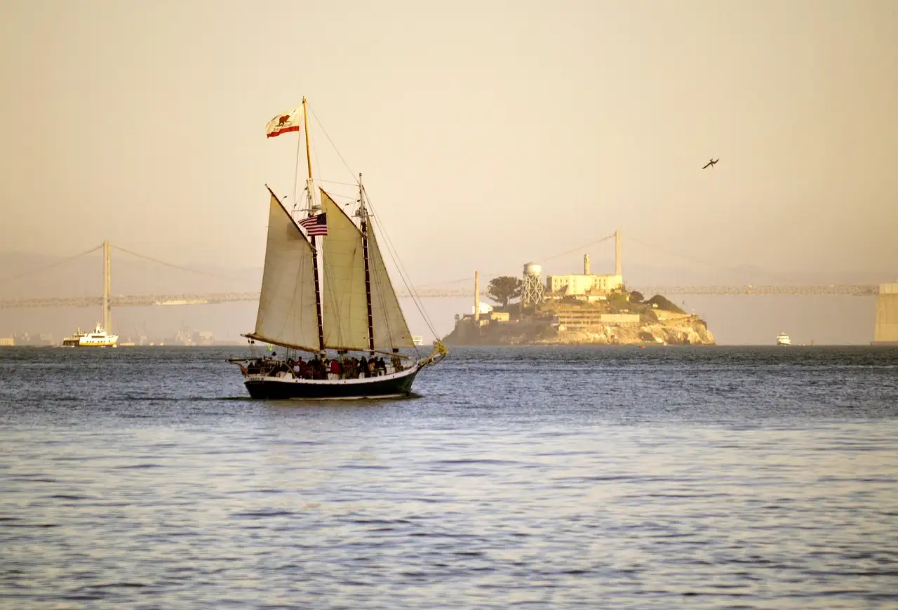 A schooner under sail on San Francisco Bay in evening light, with Alcatraz behind it