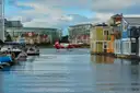 A seaplane on the water of a harbour, next to floating homes