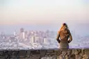 A visitor looking out over the San Francisco skyline from a stone wall on a hilltop
