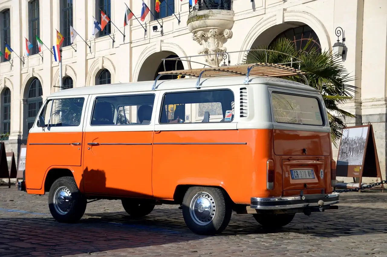 An orange and white vintage VW bus parked on a cobbled square